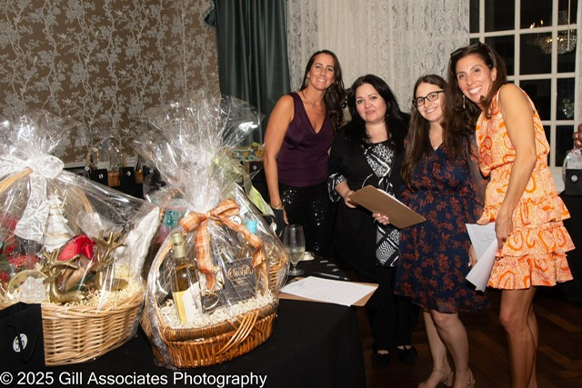 Staff and board members standing beside raffle baskets at Evening of Tastings